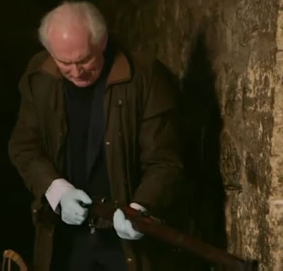 Screenshot of Dan Cruickshank holding a Lee Enfield rifle, similar to that which would have been used at the execution of Josef Jakobs on 15 August 1941. - Majesty & Mortar: Britain